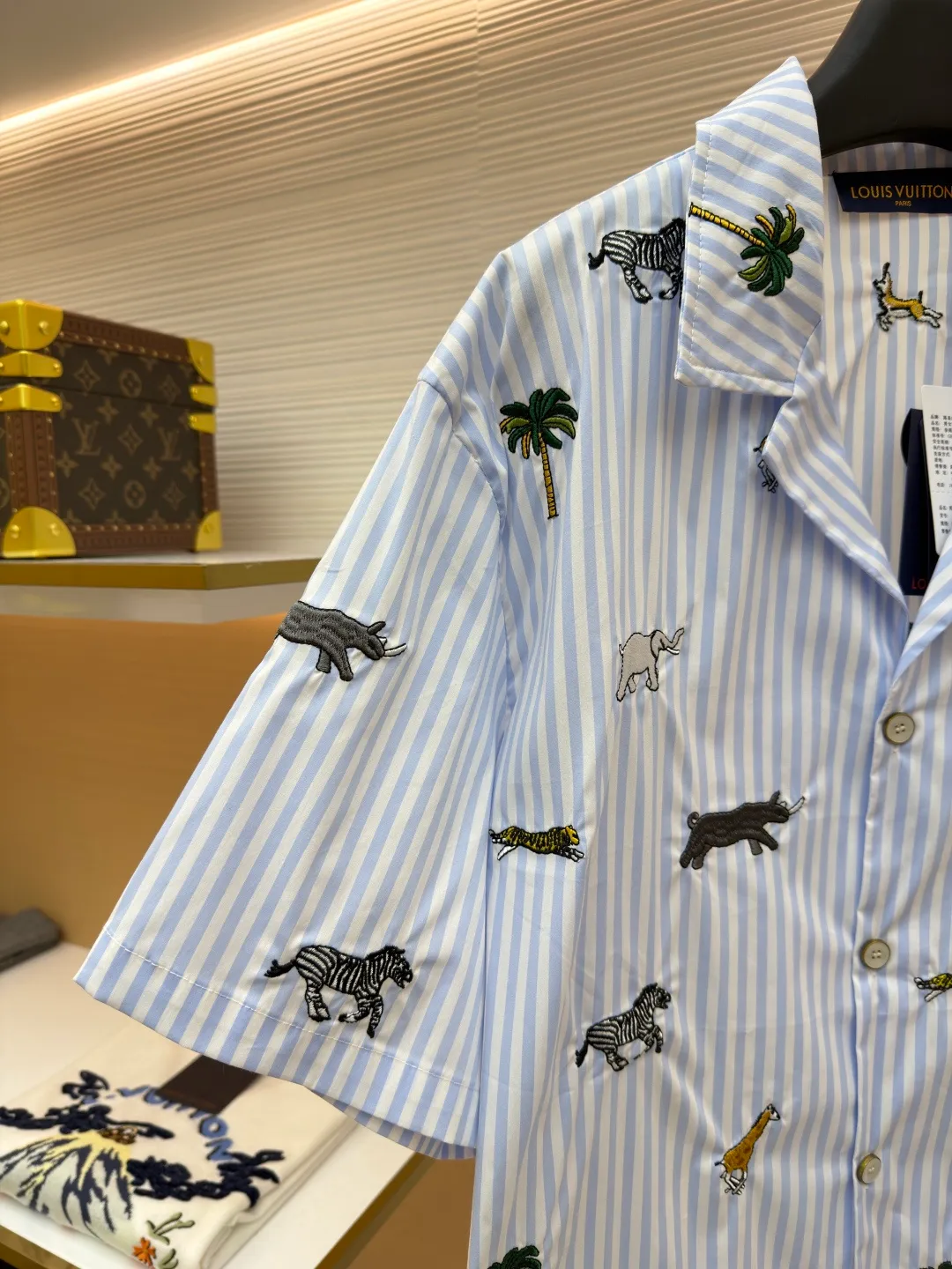 LOUIS VUITTON nostalgic style embroidered striped short-sleeved shirt with animals and plants ●Original version: Purchased and developed by 16815 ●Item number: 1682514-A65 ●Fabric: cotton fabric ●Technology: embroidery production ●Color: blue ●Version: fitted version ●Weight: about 220 grams ●Size: S-M-L-XL ●Description: This LOUIS VUITTON striped animal embroidery short-sleeved shirt is made of high-count pure cotton poplin fabric. After pre-washing process, it feels smooth and breathable. It has both drape and stiffness, and is not easy to wrinkle and deform. The blue and white vertical stripes on the body are woven with yarn-dyed technology, and the texture is clear and does not fade. The animal and coconut tree patterns are presented with sophisticated embroidery technology. The embroidery threads are full of color and the stitches are dense. The patterns are three-dimensional and vivid, forming a rich visual hierarchy with the stripe base. The shirt has a Cuban collar style, with smooth necklines, custom mother-of-pearl buttons at the placket, and a warm texture. The overall shape is loose, the shoulder joints are straight and fine, the cuffs are cuffed with exquisite craftsmanship, custom accessories and three logos are complete, and the details are full of luxury craftsmanship. It is suitable for casual vacations and daily outings, etc. The overall wiring is straight and delicate, the fabric is comfortable and soft, and the color is consistent without color difference. It can be matched with the same style to create a fashionable look and control various occasions. Customized accessories, complete with three standards, same style for men and women!